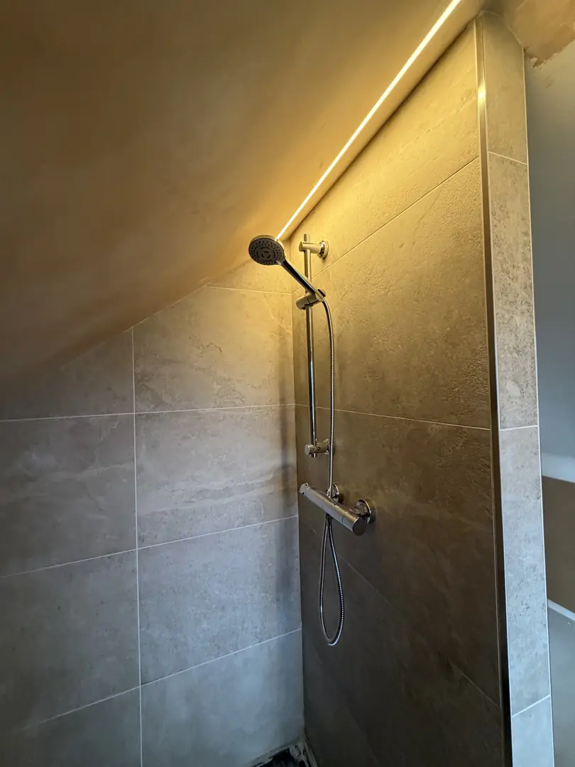 Loft bathroom installation with chrome thermostatic shower and LED strip lighting in Bridgend